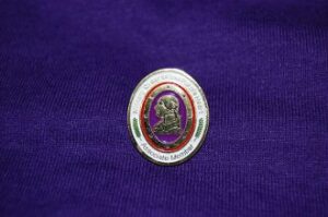 Oval pin with profile on purple fabric.