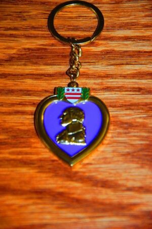 Purple heart medal keychain on wood surface.