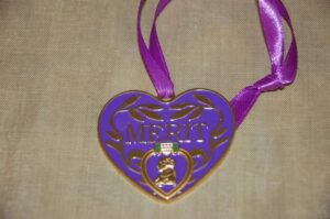 Heart-shaped purple merit medal with ribbon.