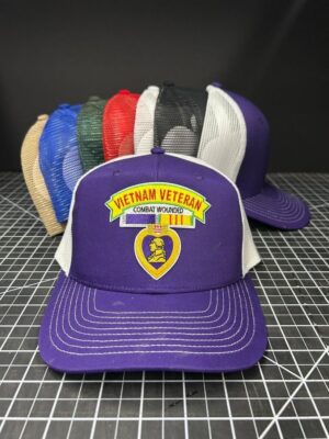 Purple Vietnam veteran hat with others behind.