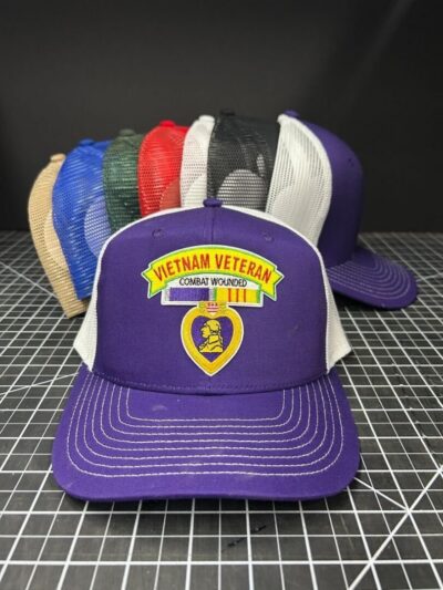 Purple Vietnam veteran hat with others behind.